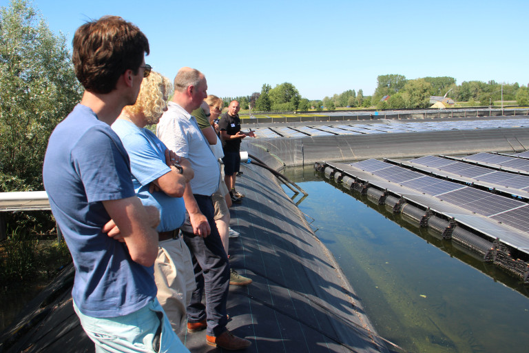 mensen bij drijvende zonnepanelen op bassin